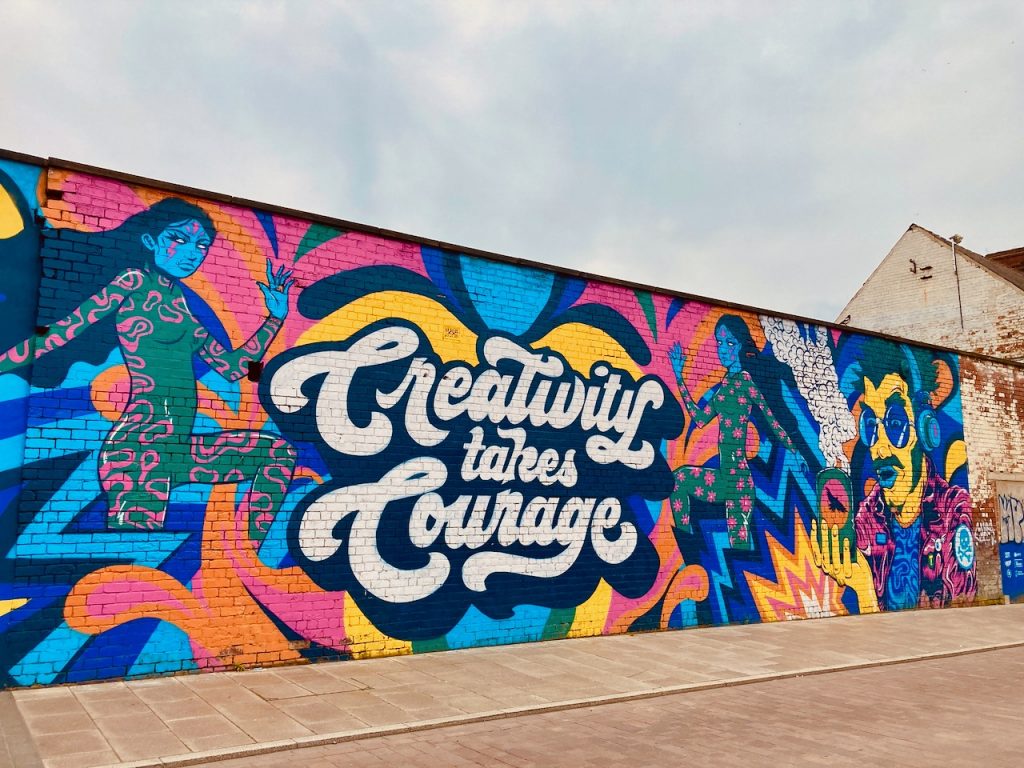 A beautiful, colourful street mural which says 'Creativity takes courage' 